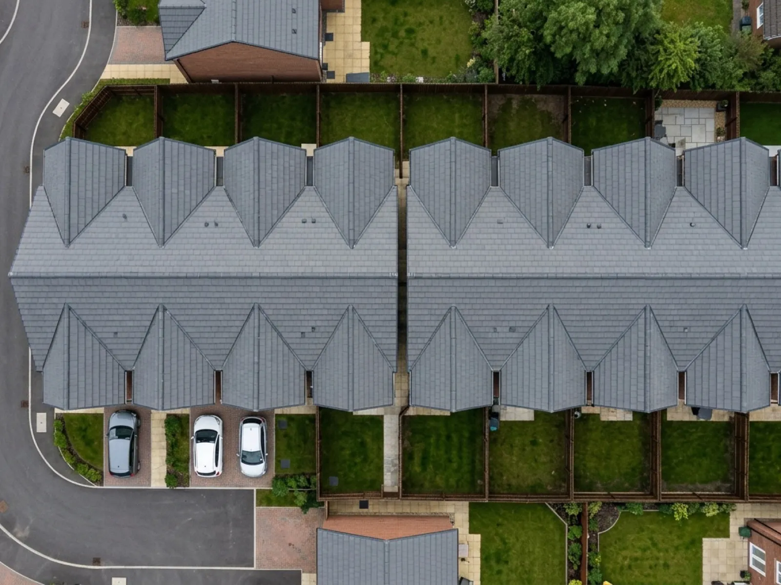 Aerial view of grey concrete tile roofs on a row of new build homes with ridge lines and verges visible from directly above